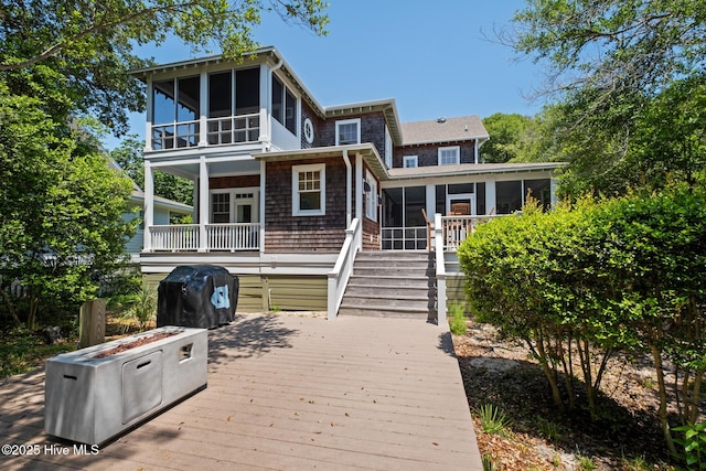 back of house featuring a sunroom, a wooden deck, and stairs