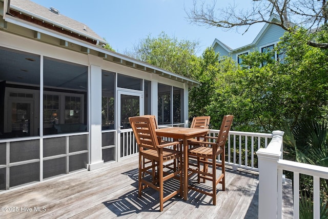 deck featuring a sunroom and outdoor dining area