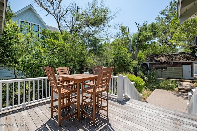 deck featuring outdoor dining area, an outdoor structure, and a storage shed