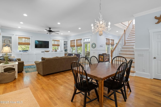 dining room featuring ornamental molding, a decorative wall, stairway, a wainscoted wall, and light wood finished floors