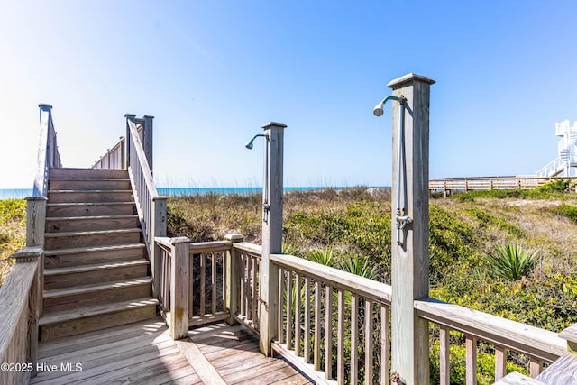 wooden terrace featuring stairs and view of water and beach