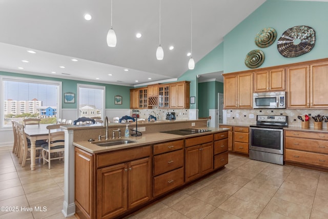 kitchen featuring stainless steel appliances, a sink, backsplash, light tile patterned flooring, and wainscoting