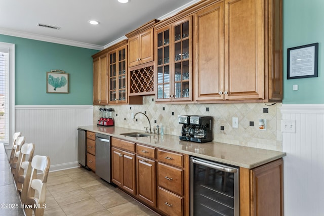 kitchen featuring beverage cooler, a wainscoted wall, a sink, dishwasher, and brown cabinetry