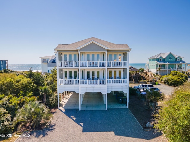 view of front of property with a balcony, a carport, a water view, and driveway