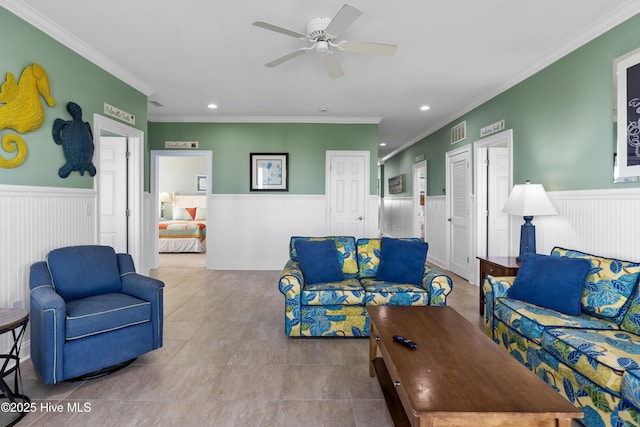 tiled living area featuring a wainscoted wall, ornamental molding, recessed lighting, and ceiling fan