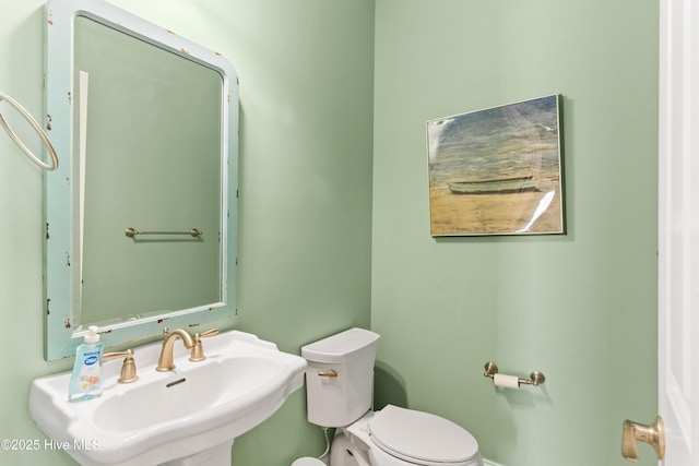 half bath featuring a sink, toilet, and baseboards