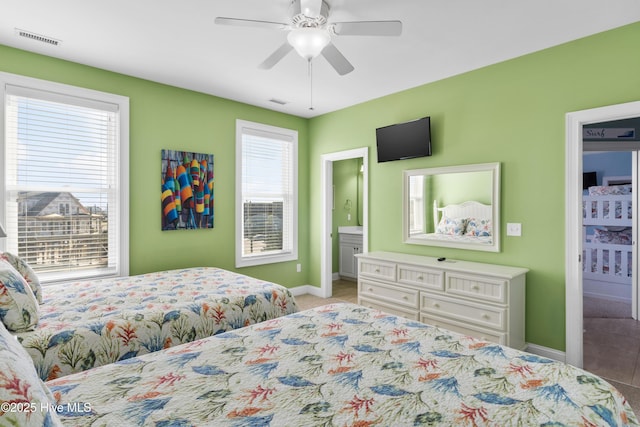 carpeted bedroom with baseboards, multiple windows, ceiling fan, and ensuite bathroom