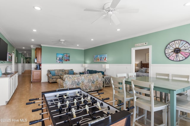 rec room with ceiling fan, crown molding, a wainscoted wall, and recessed lighting