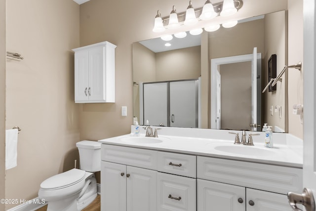 bathroom featuring a shower stall, toilet, and double vanity