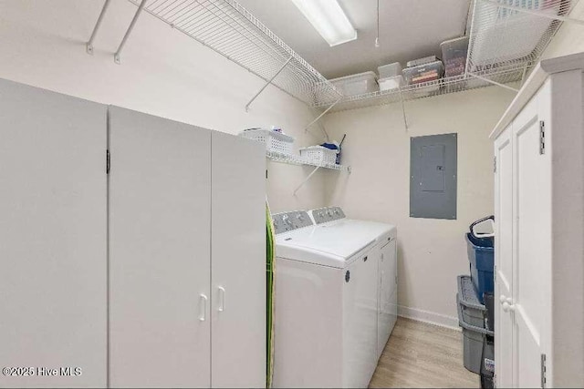 washroom featuring electric panel, washing machine and clothes dryer, light wood-style floors, and baseboards