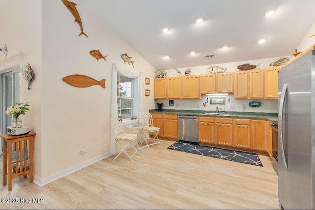 kitchen with stainless steel appliances, vaulted ceiling, light wood-type flooring, a sink, and dark countertops