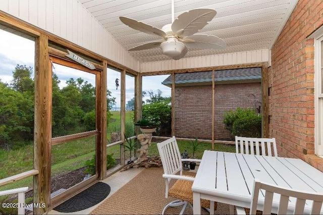 sunroom with a ceiling fan, outdoor dining space, and vaulted ceiling