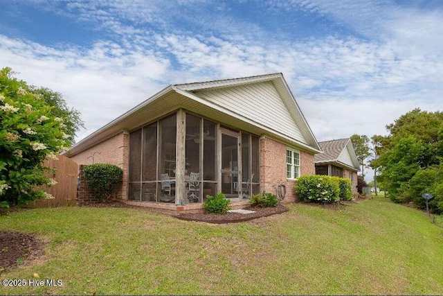 back of property with a yard, a sunroom, and brick siding