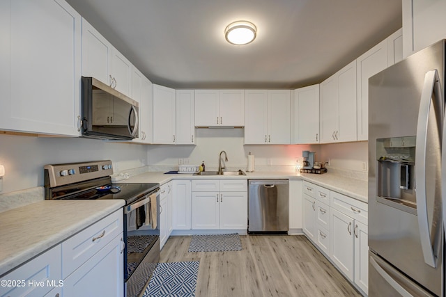 138 Cherokee Trl, Wilmington, NC 28409 - kitchen featuring stainless steel appliances, a sink, light wood-style flooring, white cabinetry, and light countertops