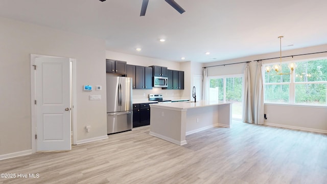 kitchen featuring appliances with stainless steel finishes, a sink, light wood-style floors, a ceiling fan, and baseboards