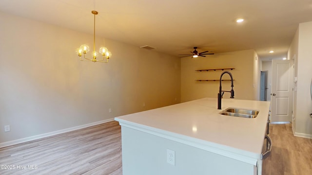 kitchen with a sink, light wood finished floors, a ceiling fan, an island with sink, and recessed lighting