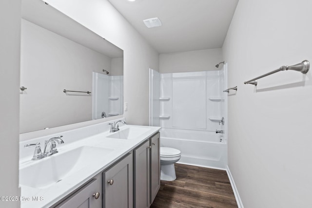 full bathroom with toilet, wood finished floors, double vanity,  shower combination, and baseboards