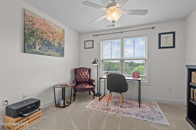 carpeted office space featuring baseboards and a ceiling fan