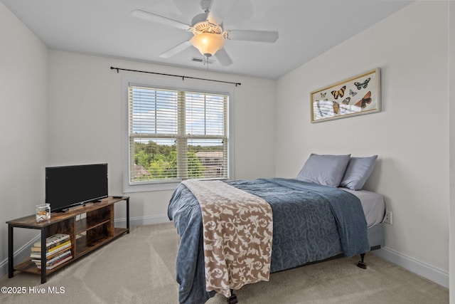 bedroom featuring light colored carpet, multiple windows, baseboards, and a ceiling fan