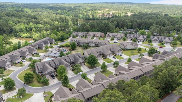 aerial view of property and surrounding area featuring a forest and nearby suburban area