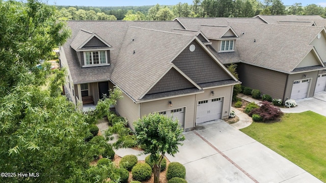 craftsman-style house featuring driveway, a front lawn, roof with shingles, and an attached garage