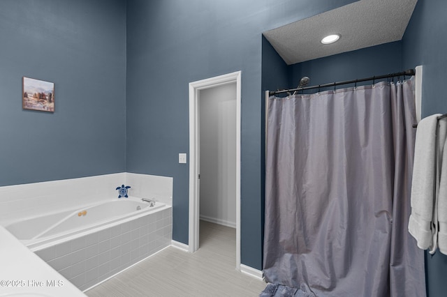 bathroom with a garden tub, baseboards, a textured ceiling, and tile patterned flooring