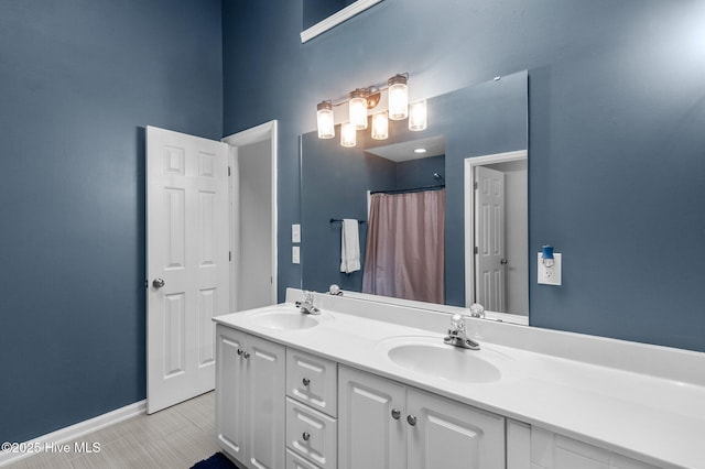 full bath with double vanity, baseboards, and a shower with shower curtain