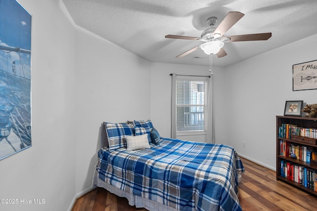 bedroom featuring wood finished floors, a textured ceiling, baseboards, and ceiling fan