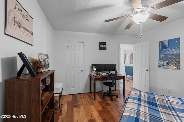 bedroom with wood-type flooring, a desk, a ceiling fan, and a textured ceiling