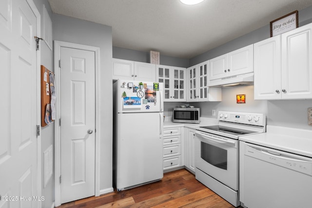 kitchen with white appliances, under cabinet range hood, white cabinetry, wood finished floors, and light countertops