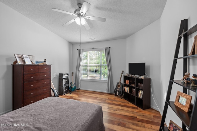 bedroom with a textured ceiling, wood finished floors, and a ceiling fan