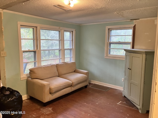 living area with dark wood-type flooring, a textured ceiling, ornamental molding, and baseboards
