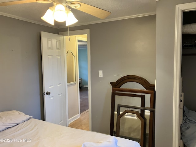 bedroom with light wood finished floors, ornamental molding, a ceiling fan, and baseboards