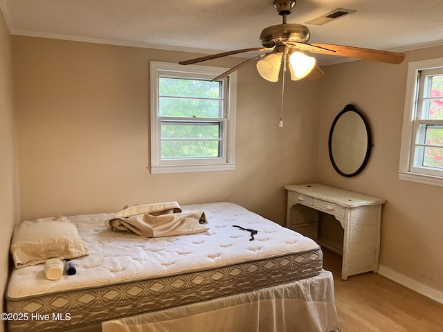 bedroom featuring ornamental molding, light wood finished floors, baseboards, and ceiling fan