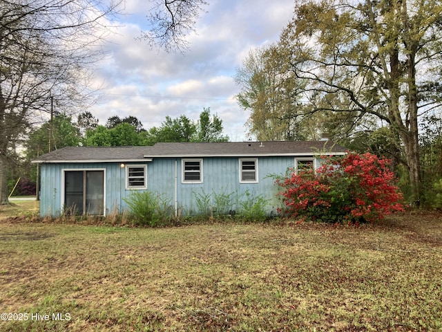 rear view of property featuring a yard and roof with shingles