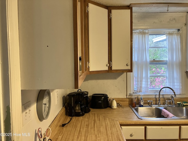 kitchen with a sink, light countertops, and white cabinetry