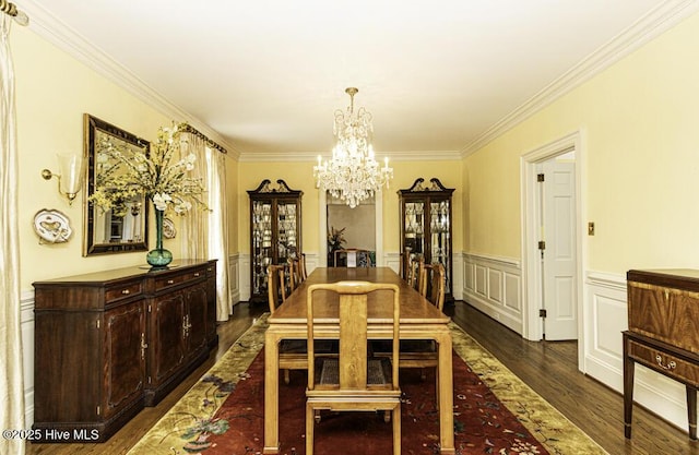 dining room with a chandelier, crown molding, dark wood finished floors, and wainscoting