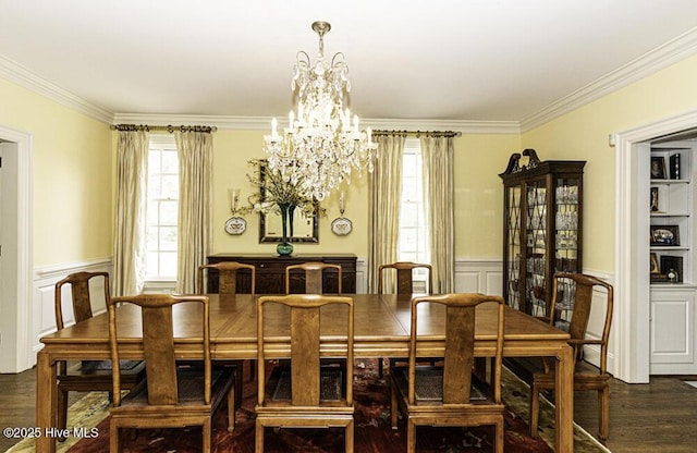 dining space featuring a chandelier, healthy amount of natural light, crown molding, a wainscoted wall, and wood finished floors