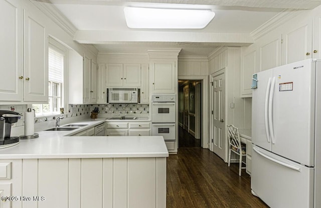 kitchen with white appliances, a sink, crown molding, a peninsula, and decorative backsplash
