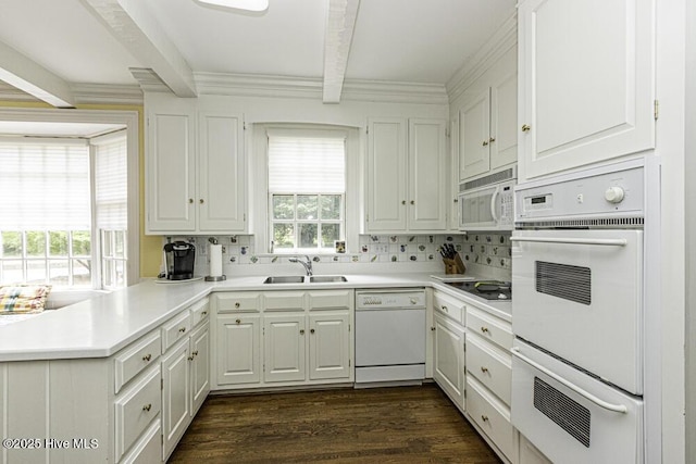 kitchen with white appliances, beamed ceiling, a sink, backsplash, and a peninsula