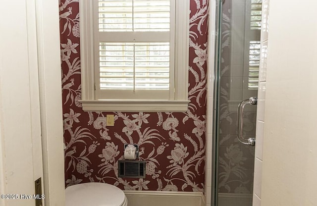 full bathroom with wallpapered walls, a stall shower, and toilet