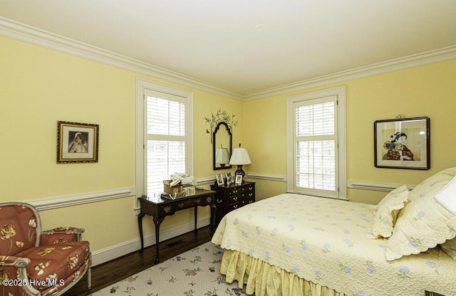 bedroom with ornamental molding, wood finished floors, multiple windows, and baseboards