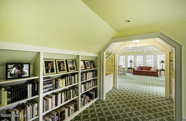 corridor featuring carpet flooring, lofted ceiling, and built in shelves
