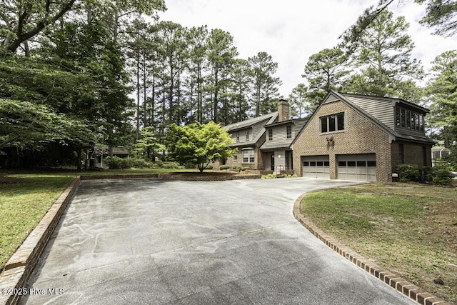 view of front of home with concrete driveway, an attached garage, a chimney, and a front lawn