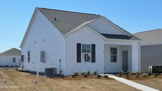 view of front facade featuring cooling unit, a shingled roof, and board and batten siding