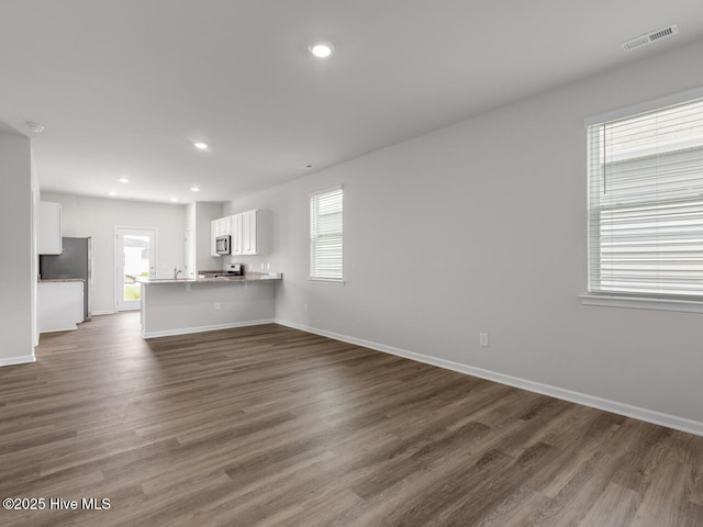 unfurnished living room featuring dark wood-style floors, baseboards, and recessed lighting