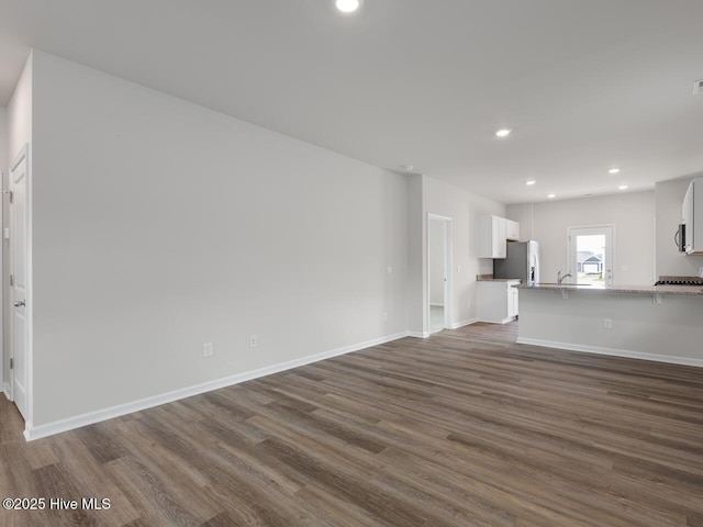 unfurnished living room featuring dark wood finished floors, recessed lighting, and baseboards