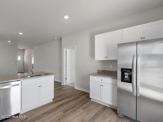 kitchen featuring appliances with stainless steel finishes, a sink, white cabinetry, light stone countertops, and recessed lighting