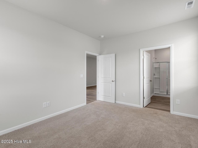 unfurnished bedroom featuring carpet flooring, baseboards, and ensuite bathroom