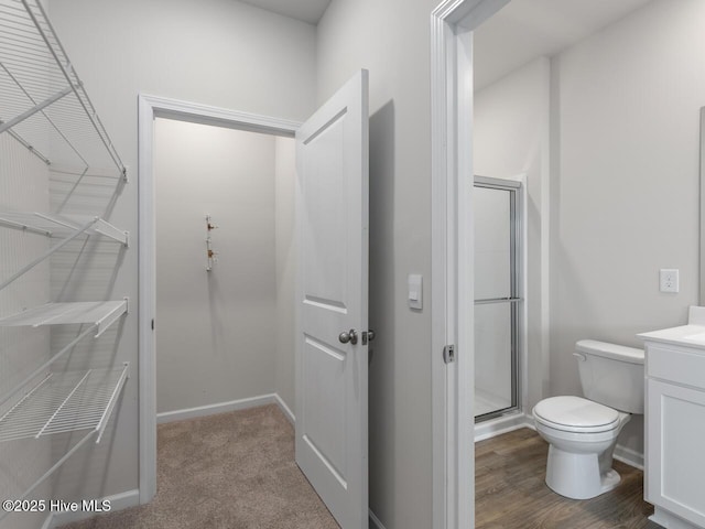 bathroom with toilet, a shower stall, vanity, and baseboards